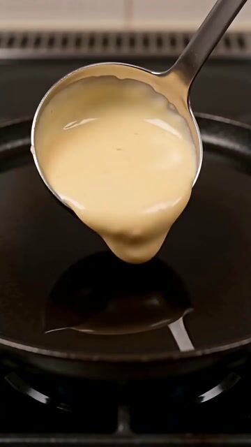 Three-shot hard-cut sequence, 8 seconds total, vertical 9:16, hyper-real documentary macro cooking footage intercut with non-photoreal 2D line-art cartoon inserts, 24fps, real-time speed throughout, no slow motion.

SHOT 1 (0:00–0:01): Overhead top-down framing on a kitchen counter, a hand's fingers gripping a light-blue capacitive stylus enters frame from the lower right and taps once onto a steel ladle of pale yellow pancake batter mid-pour onto a hot griddle. On contact, the entire frame instantly converts into a flat black-and-yellow 2D line-art cartoon sketch — bold black outlines, solid yellow fill, no gradients, no shading, screen-printed poster look. The transformation happens exactly once, is instantaneous (no dissolve, no morph animation, a hard visual swap on the tap), and the batter's pour position and shape are identical in both the live-action and cartoon frame at the moment of the cut.

SHOT 2 (0:01–0:04): Hard cut, same overhead top-down angle, now rendered as the black-and-yellow cartoon: the animated batter sits on a cast-iron griddle, hand-drawn bubbles rising through it one by one, a cartoon knob of butter melting and spreading in thin outlined rivulets at the edges. A stylus tap enters frame and touches the center of the pancake; on contact the cartoon instantly converts back into live-action — a real golden-brown pancake mid-flip above the same griddle, sizzling, small droplets of butter spitting at the edges, steam rising. The pancake's size, position, and browning state at the instant of the cut match exactly what the cartoon version showed the frame before — nothing is re-shown or reset.

SHOT 3 (0:04–0:08): Hard cut to a dark ceramic plate shot from a slight high angle, first as the black-and-yellow cartoon: a stack of three outlined pancakes with looping hand-drawn steam lines rising off the top, animated powdered sugar sifting down from just above frame in a fine dotted trail. A final stylus tap touches the plate and it instantly converts into a live-action gourmet dish: the same three-pancake stack now photoreal, dusted with real powdered sugar, fresh raspberries and blueberries scattered beside it, two mint leaves placed on top, and maple syrup pouring in a slow amber ribbon from a small wooden syrup boat entering from the upper right, pooling at the base of the stack. The stack's height, position on the plate, and camera framing stay identical across the cut.

CAMERA: fixed overhead rig, 47° FOV equivalent to a 40mm lens, locked focus at griddle/plate height, no camera movement within any shot — only the hard cuts change what's shown. No fisheye, no zoom, no gimbal drift, no camera shake.

PHYSICS: batter has real fluid viscosity and settles under gravity; butter melts and pools believably; steam in the live-action shots rises and dissipates with natural buoyancy and air current drift; syrup pours as a continuous ribbon with correct trailing thickness, no floating or clipping of any prop.

LIGHTING: single soft overhead kitchen light, warm 4000K, consistent direction and intensity across both the live-action and cartoon renders of each shot so the transformation reads as a style swap, not a lighting change.

AUDIO: diegetic only — batter sizzling and popping on contact with the griddle, a light plastic-on-glass "tap" sound each time the stylus touches down, butter crackling, powdered sugar's soft sifting hiss, syrup's slow pour and light splash into the pool at the base of the stack. No music, no narration, no voiceover, no on-screen text.

CLOSING LOCK: no logos, no watermarks, no additional hands or people beyond the single tapping hand, no on-screen text of any kind. The video ends holding on the finished gourmet plate — no fade out, no freeze frame.